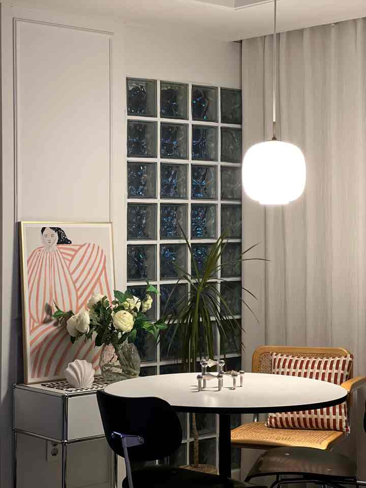 White and brown accented living dining space featuring a pendant light and rattan armchair with modern natural interior style
