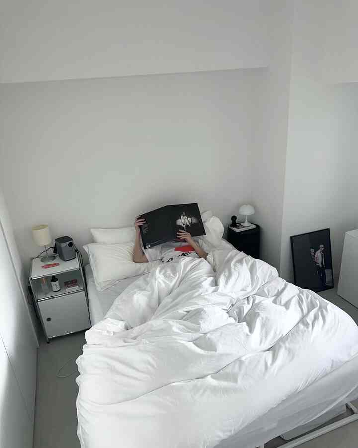 白を基調とした寝室、白いベッドカバーとナイトテーブルが配置されたシンプルでモダンな雰囲気のインテリア