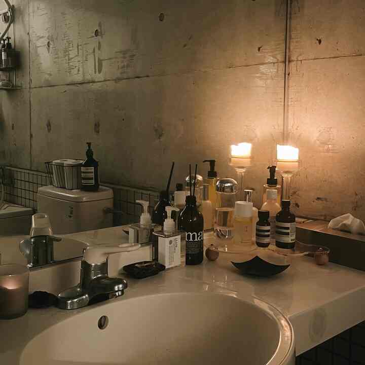 温かみのある照明のホテルライクなバスルーム、白い洗面台とグレーのコンクリート壁が調和した空間