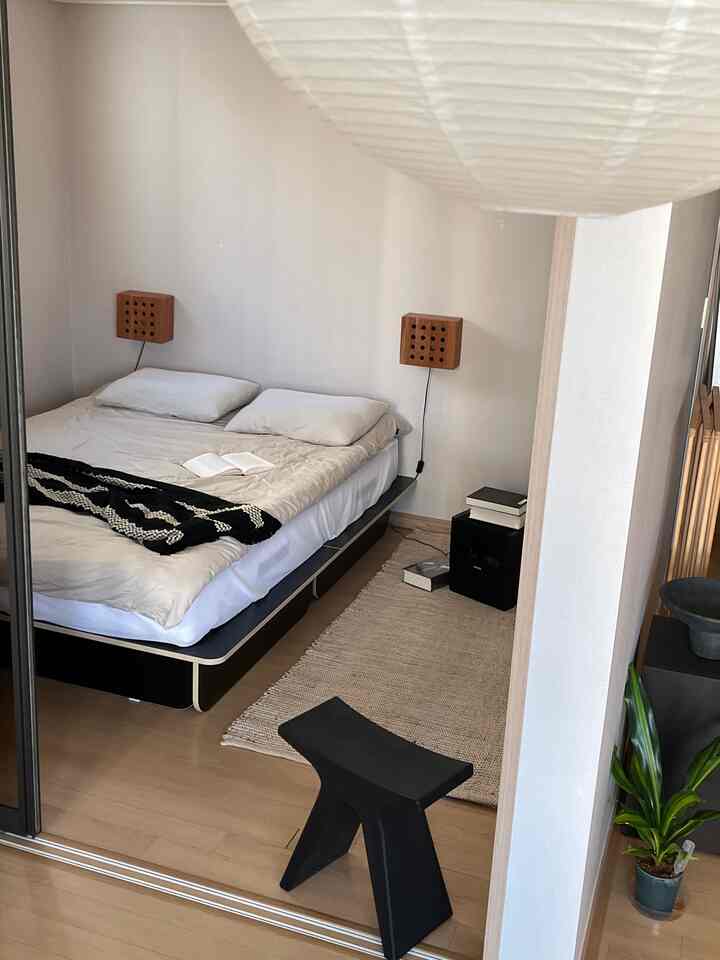 Black and natural wood-tone studio bedroom featuring a storage bed frame and rug creating a cozy atmosphere