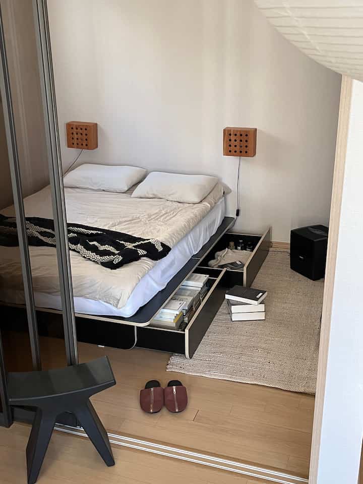 Natural beige-toned bedroom featuring a black bed frame with storage drawers and a beige rug, creating a cozy atmosphere
