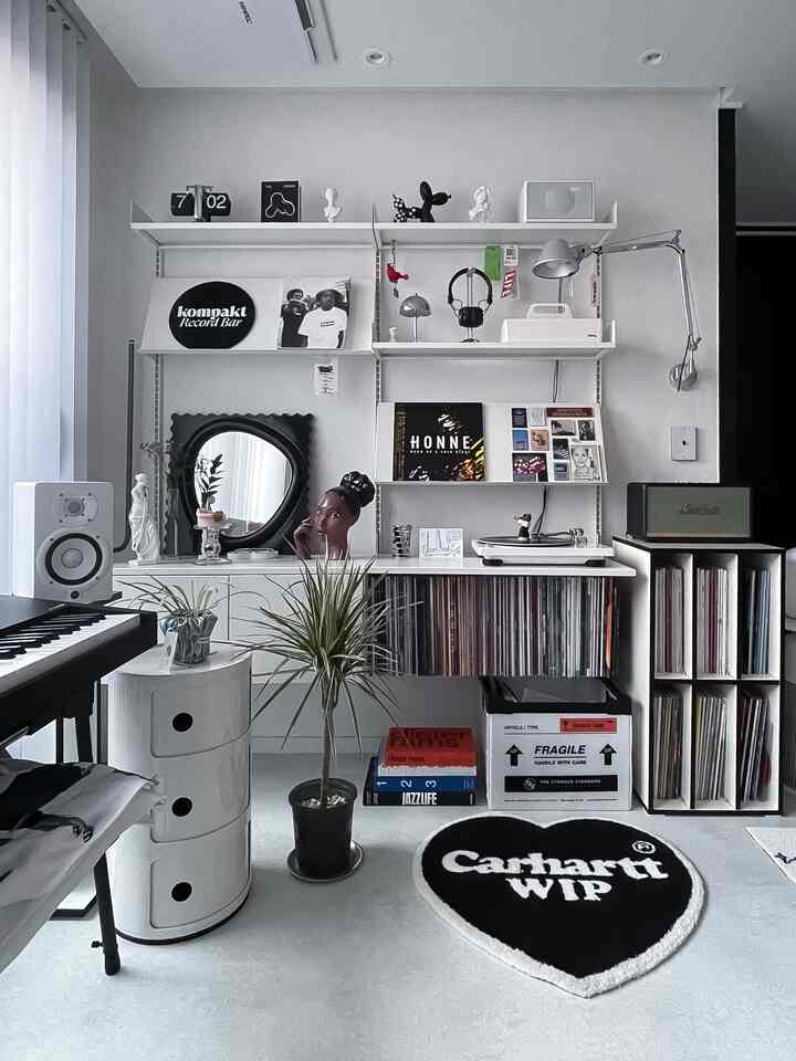 White-toned living room music listening space featuring wall shelves, LP records, turntable, and interior objets with a simple and clean atmosphere