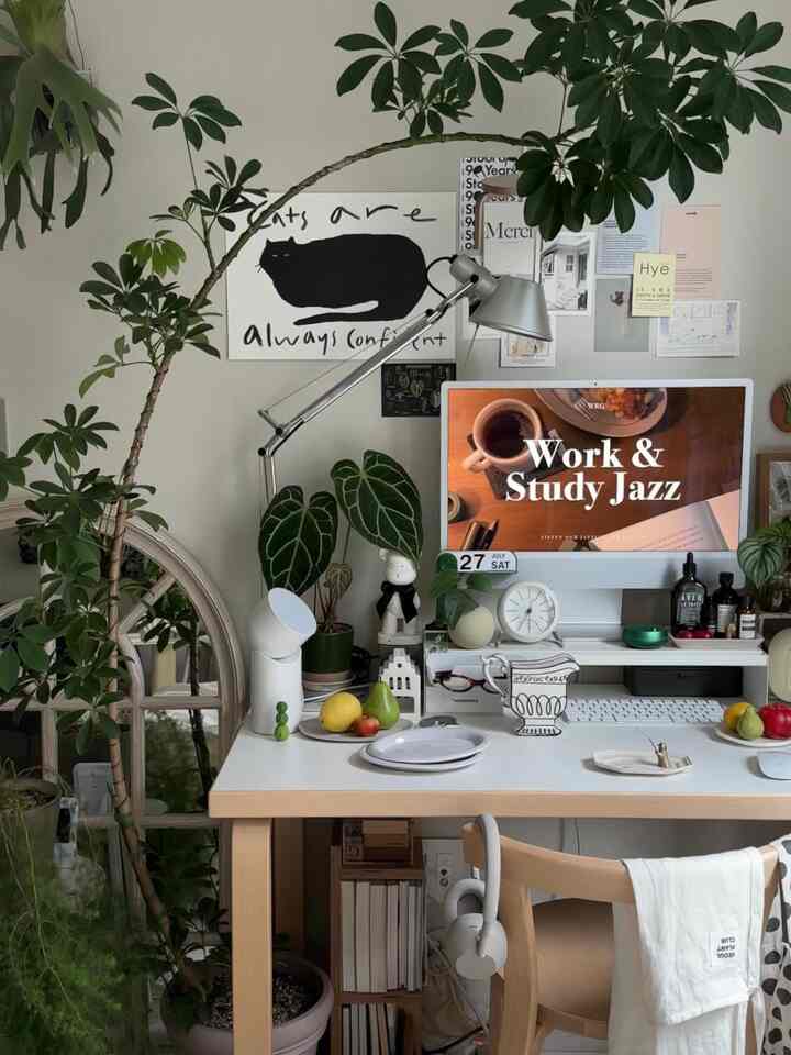 White and natural toned home office featuring an Artek chair and abundant plants creating a cozy desk interior