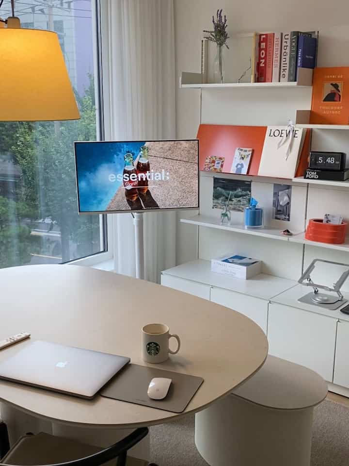 Natural beige and white toned home office featuring a modern desk with laptop and coffee mug, creating a cozy atmosphere