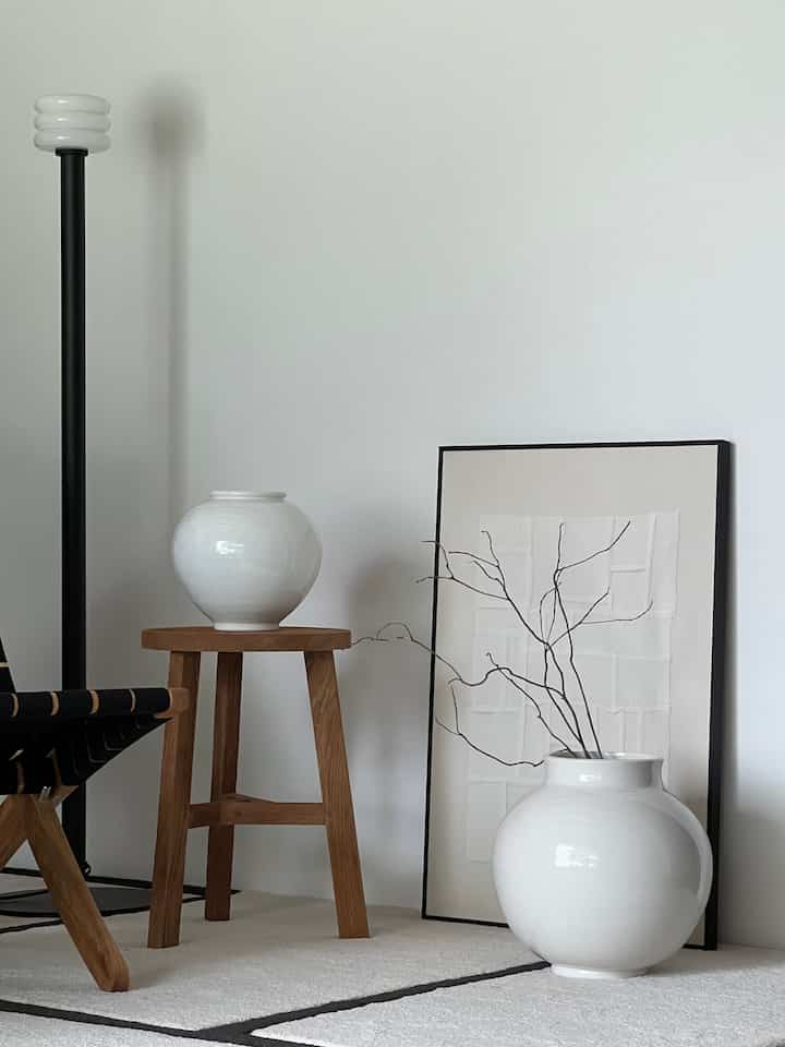 A living room with soft white and natural wood tones featuring elegant Korean traditional moon jars with flowing curves and minimalist decor elements