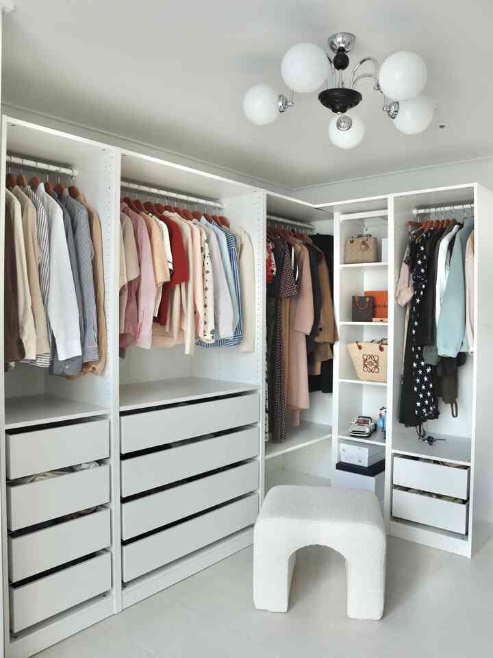 ホワイトトーンのウォークインクローゼット、整理された服と引き出しが配置されたシンプルな空間