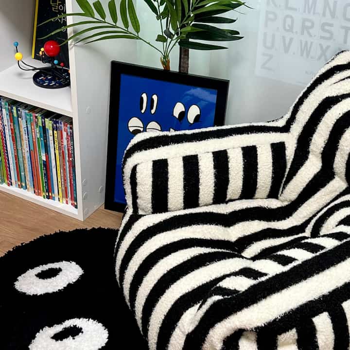 Black and white striped sofa and bookshelf in a kids' room, black and white tones create a cozy and neat atmosphere