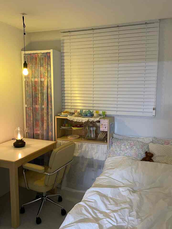 ホワイトとベージュのトーンの寝室、デスクと花柄のカーテンが温かみのある雰囲気を演出している