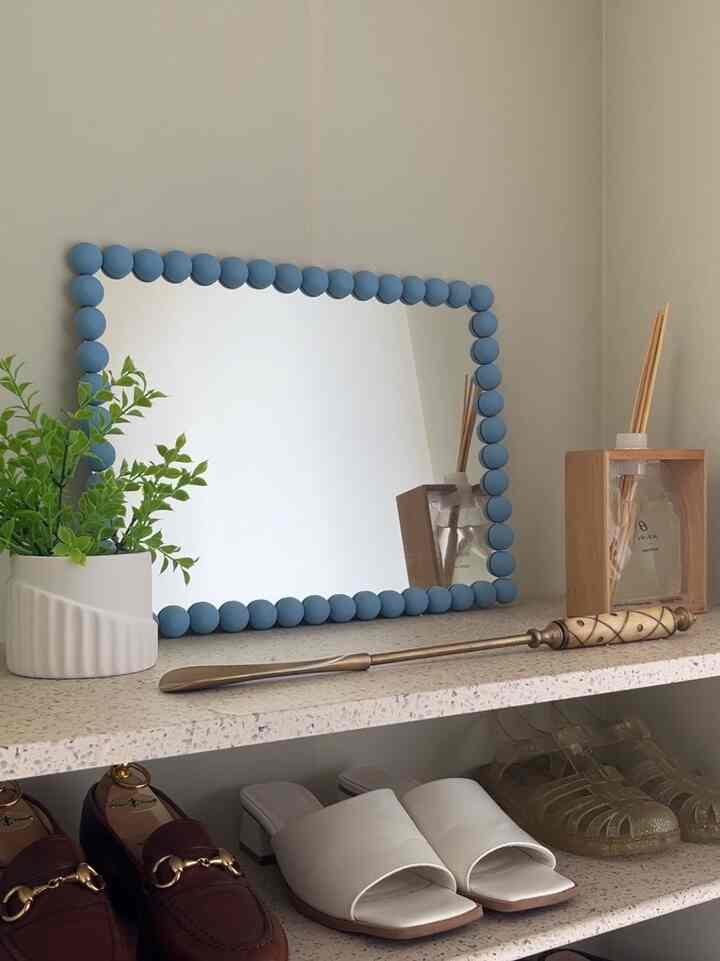 ホワイトとスカイブルーの色調の玄関、シューズラックとディフューザー、ミラーが配置された印象的な空間