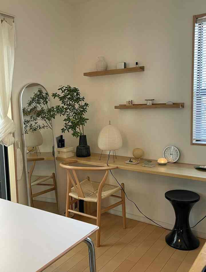 Natural-toned small home office featuring a wooden desk, chair, mirror, and a plant with a clean interior atmosphere