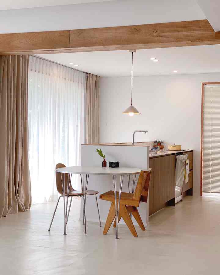 Bright kitchen space with white floor and wood tone kitchen, featuring a simple dining area