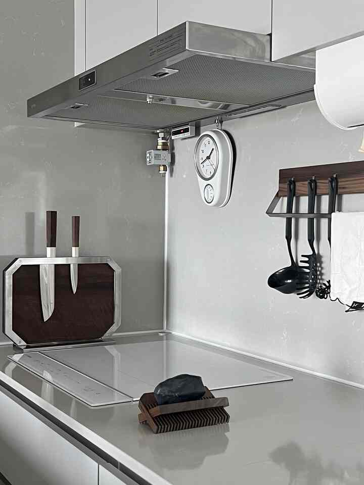 Gray and white toned kitchen featuring walnut wooden knives, kitchen utensils, and a white clock with a clean, classic interior style