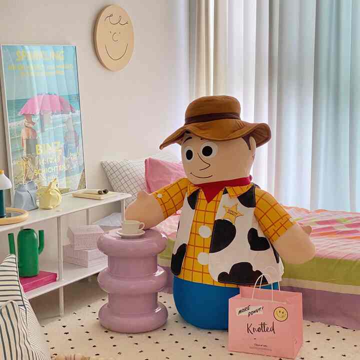 Pastel-toned bedroom featuring a Woody character bean bag and lavender stool in a cozy, cute setting