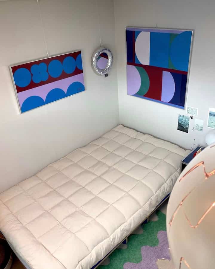 White and green toned 4.5-tatami bedroom featuring a bed with pillows and abstract posters, creating a cozy space