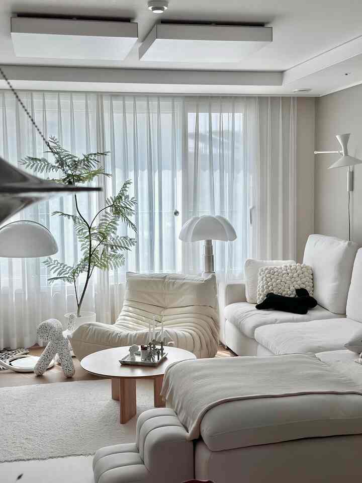 A cozy living room in white and natural tones featuring comfortable sofas and a wooden coffee table