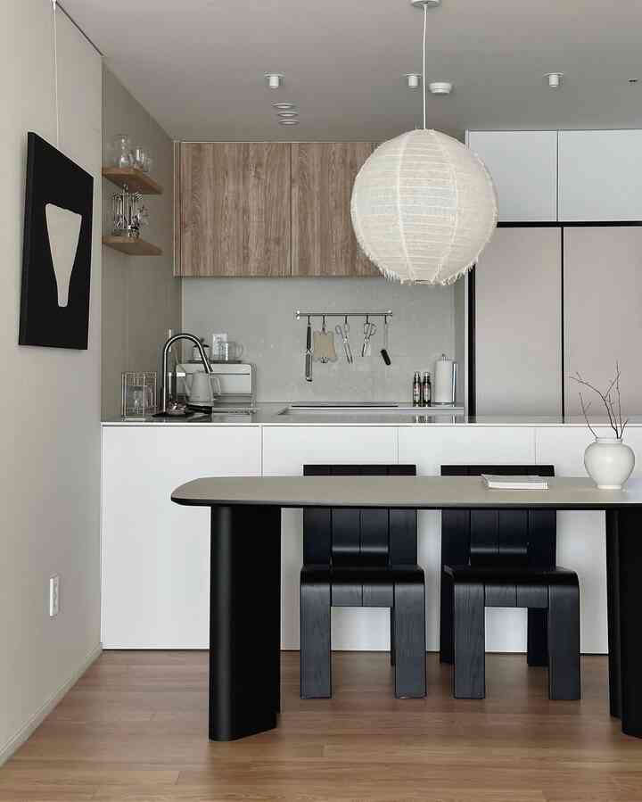 Modern dining room with a harmonious mix of white and black elements, warm wood-tone flooring and upper cabinets create cozy atmosphere