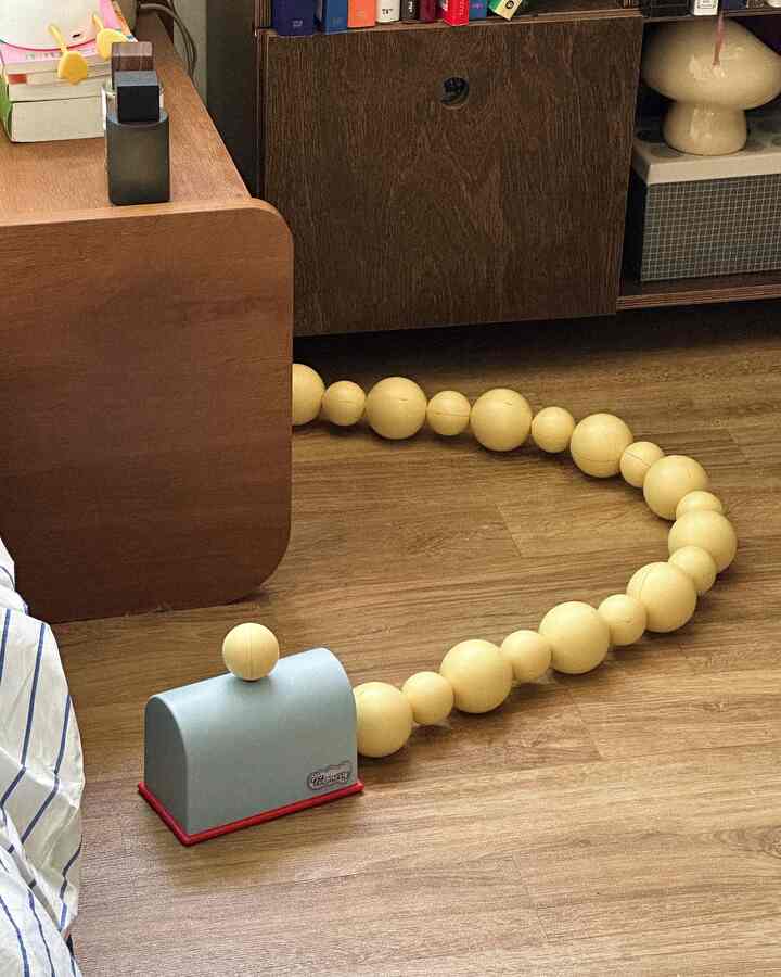 Wood tone floor and furniture space featuring a connected spherical pet toy placed on the floor