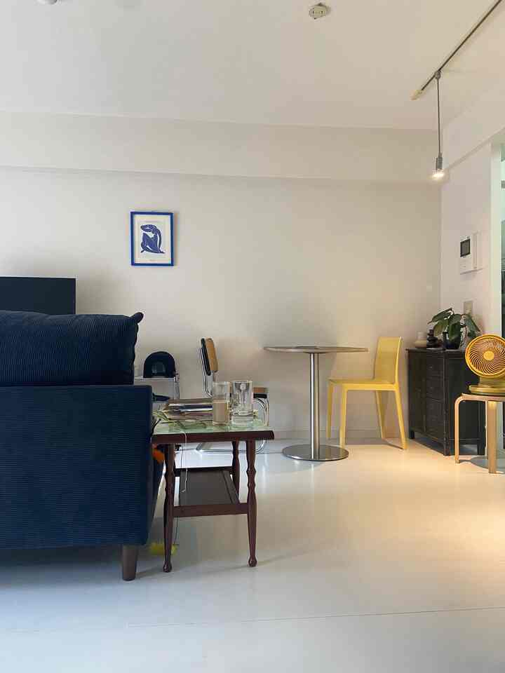 White-toned living room featuring navy sofa and yellow chairs with a clean, natural atmosphere