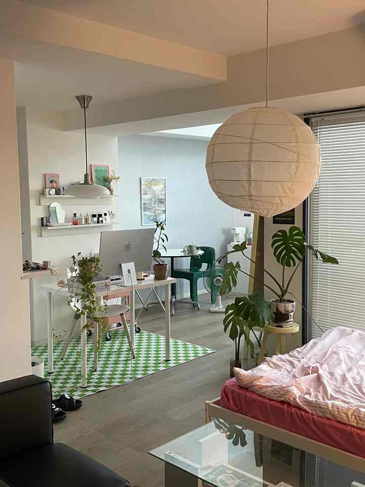 A white and green toned studio apartment featuring a bed and desk in a cozy, tidy space for two persons