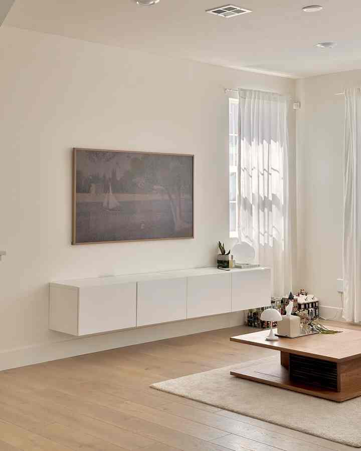 White and wood tone living room with a wall-mounted white BESTÅ shelf unit and a wood coffee table in a minimalistic space
