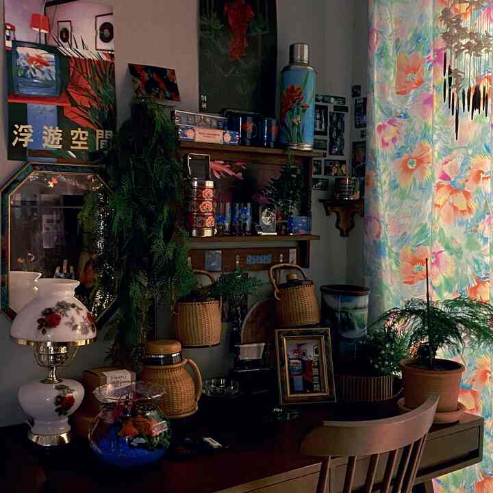 木目調と緑の植物が調和した、ポスターとオブジェが配置されたヴィンテージ感のある小さな書斎空間
