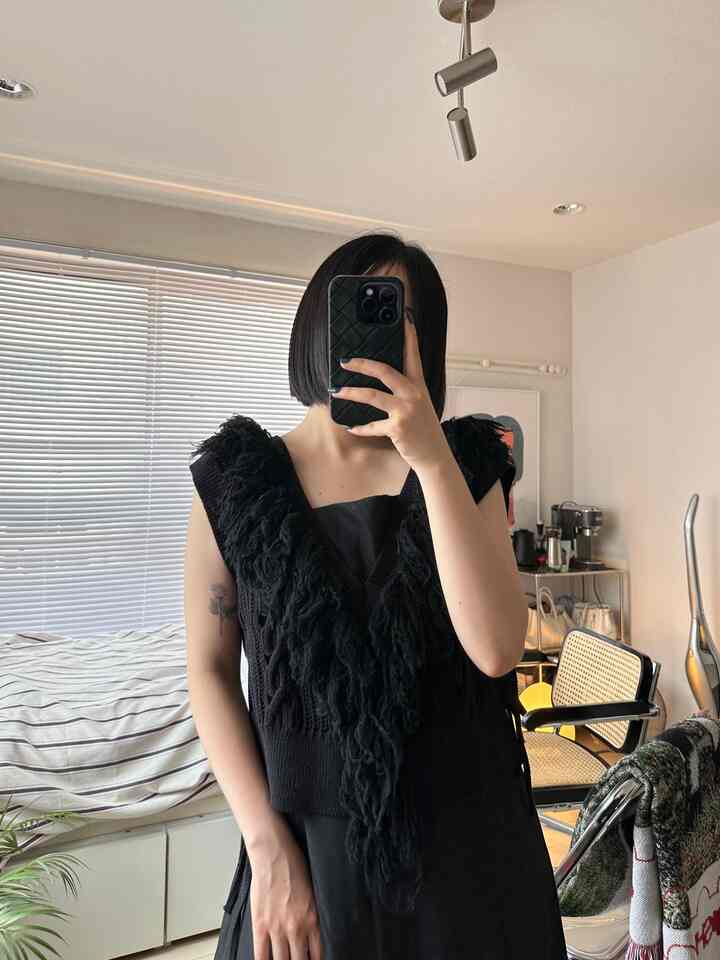 Studio apartment bedroom with white walls and blinds, person in black clothing standing in front