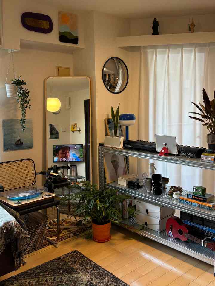 Natural color toned living room featuring steel open rack, large floor mirror, and various plants in a modern interior