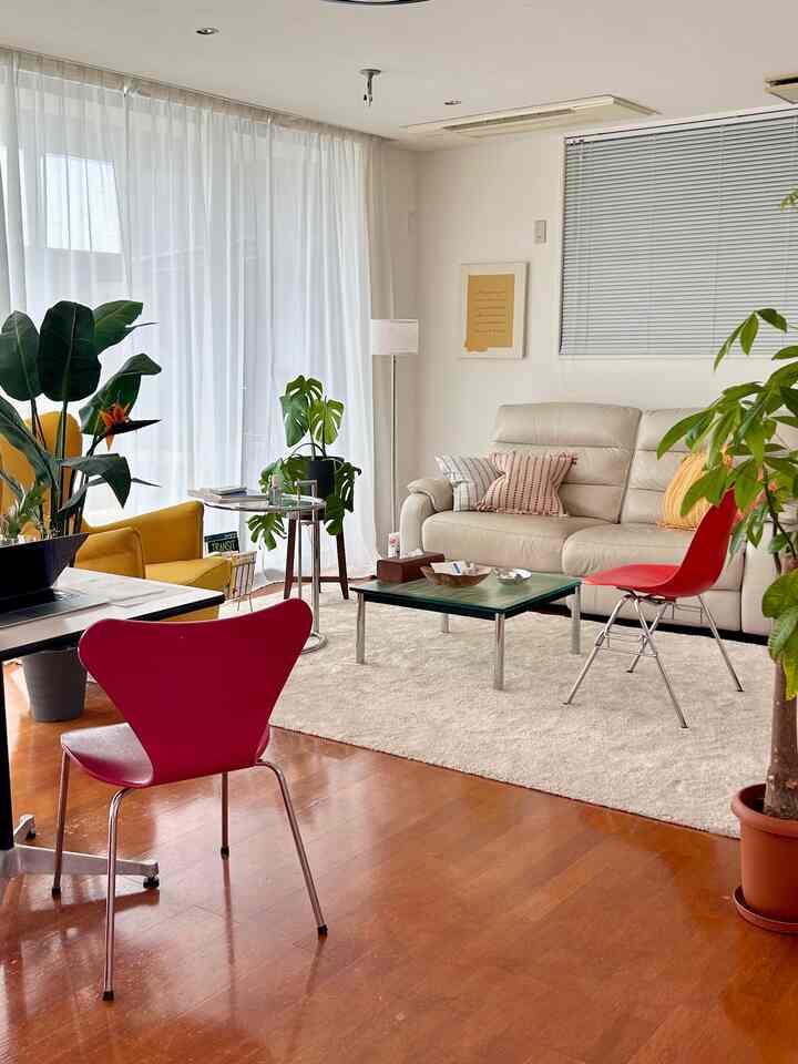 Warm wood-tone living room featuring beige sofa and red chairs