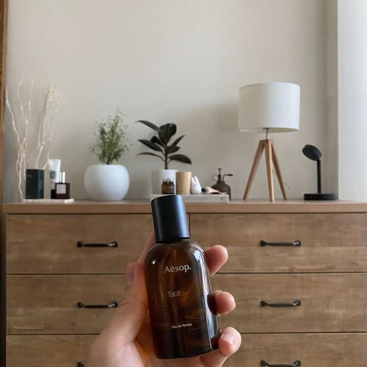 淡いベージュと木目調のナチュラルなリビングスペース、チェストの上にテーブルランプや植物が置かれた雰囲気のあるインテリア