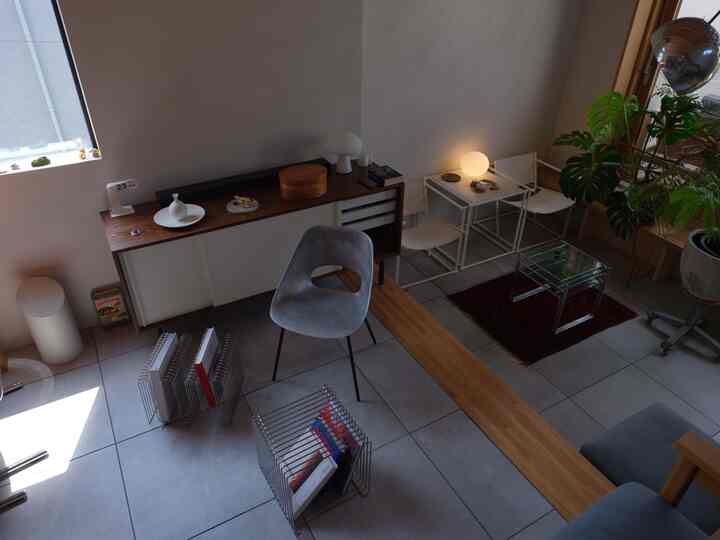 Natural-toned small modern living room featuring white and brown furniture, table lamp, and prominent plants