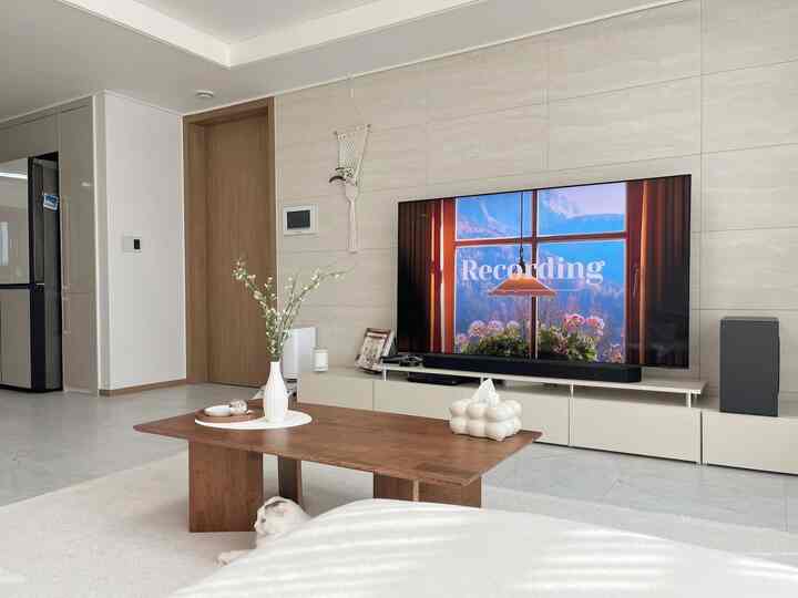 ホワイトとウッドトーンが調和したリビング、コーヒーテーブルとテレビが配置された印象的で自然なインテリア