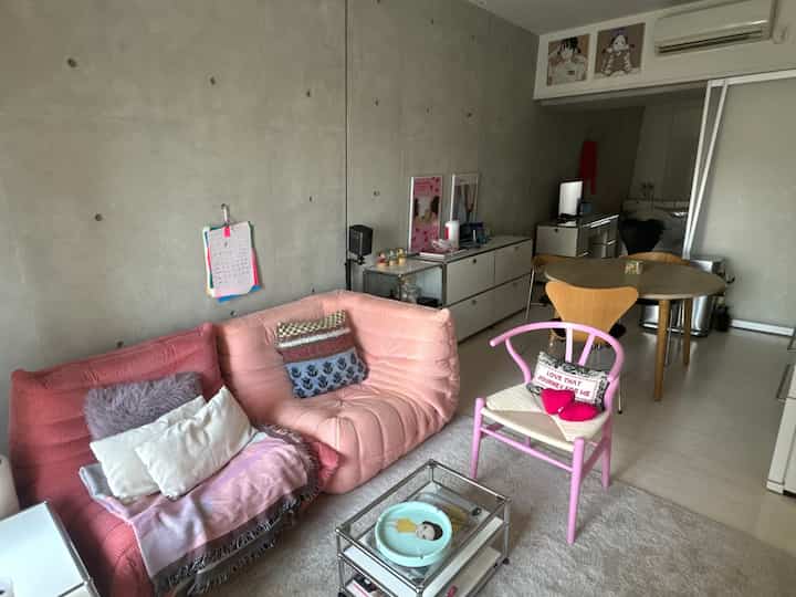 A pink and natural-toned living and dining space featuring a wooden dining table and sofa in a cozy modern interior