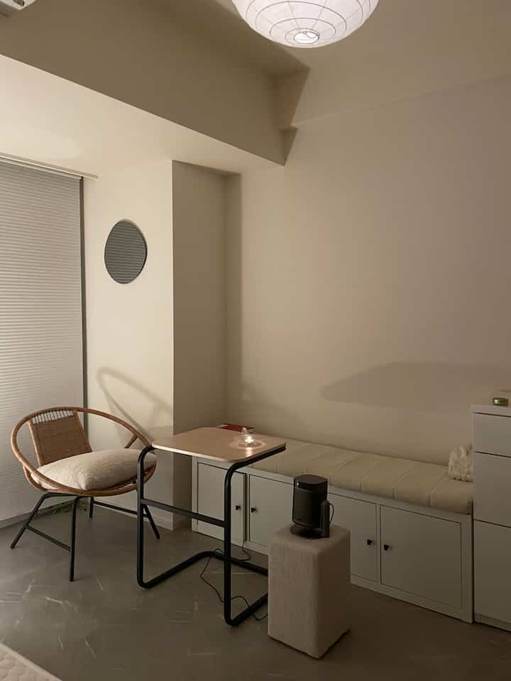 Beige-toned small living space featuring a natural rattan armchair, stool, and a simple side table for a cozy interior