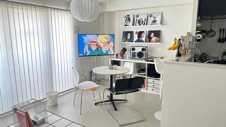 Modern living and dining room in white tones featuring a sleek dining table, vertical blinds, and clean minimalist design