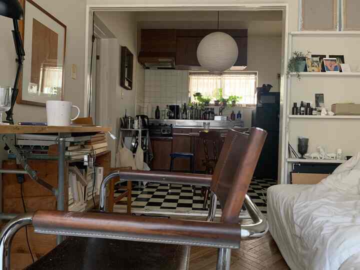 白とブラウンの木目調が調和するアパートのリビングとキッチン、チェック柄とヘリンボーンの床が印象的な空間