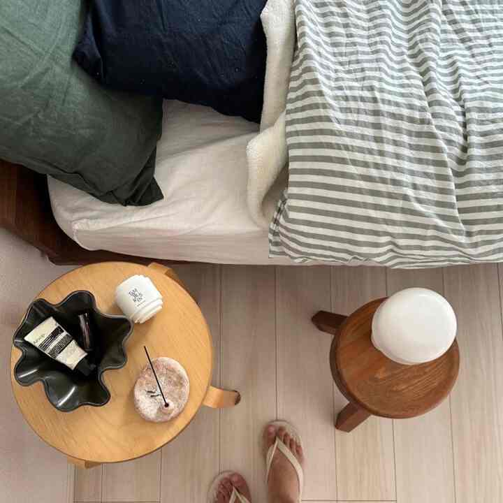 ナチュラルな木目調家具と白い寝具が配置されたモダンな寝室の落ち着いたベッドサイドスペース