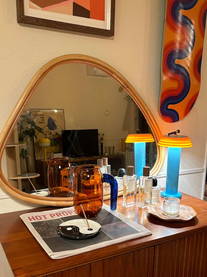 Cozy modern living room console table with warm wood tones and transparent glass accessories in front of a rattan-framed mirror