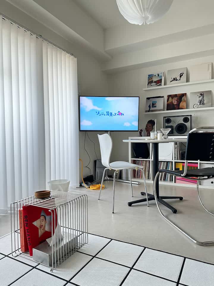 明るい白を基調としたリビング、白と黒のダイニングチェアが丸テーブルを囲み、壁にかけられたテレビがあるミニマルな韓国インテリアの空間