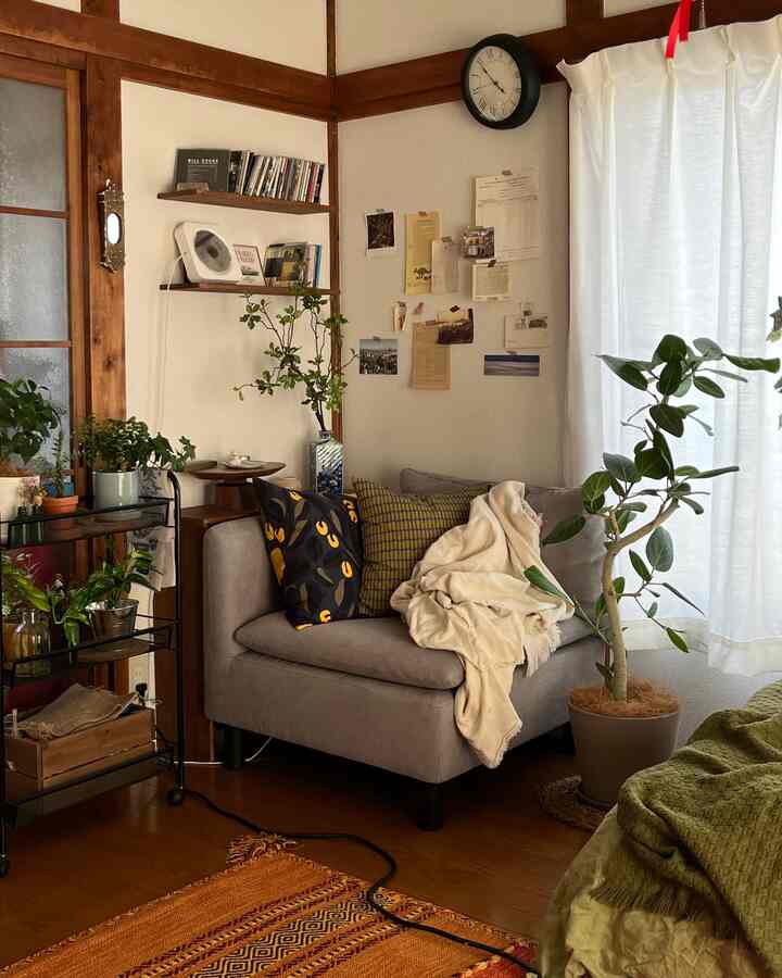 ナチュラルな色調の1人用ソファと複数の植物が配置された落ち着いたリビングのコーナー