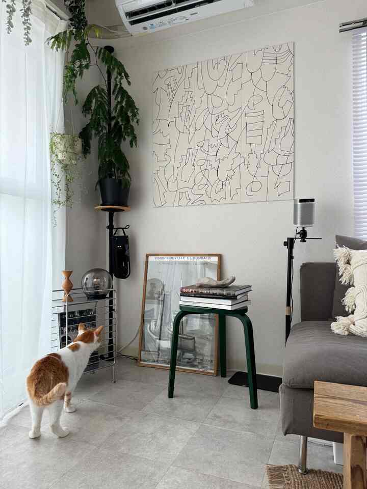 グレーとホワイトの色調のリビング、グリーンスツールと大きな植物が配置されたシンプルで北欧風の空間