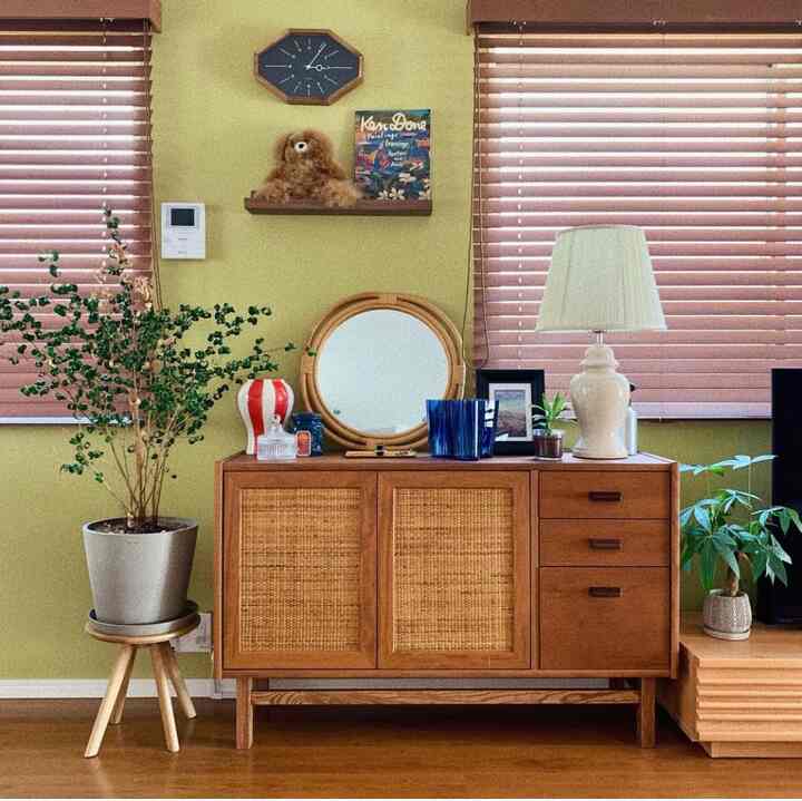 グリーンの壁と木目調キャビネット、植物が配置された北欧風の印象的なリビングスペース