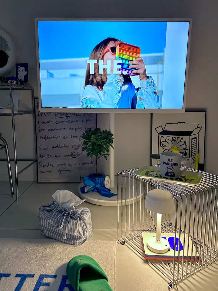 白と青のトーンのダイニングルーム、ワイヤーシェルフとティッシュカバー、テレビとダイニングチェアが配置されたモダンな空間