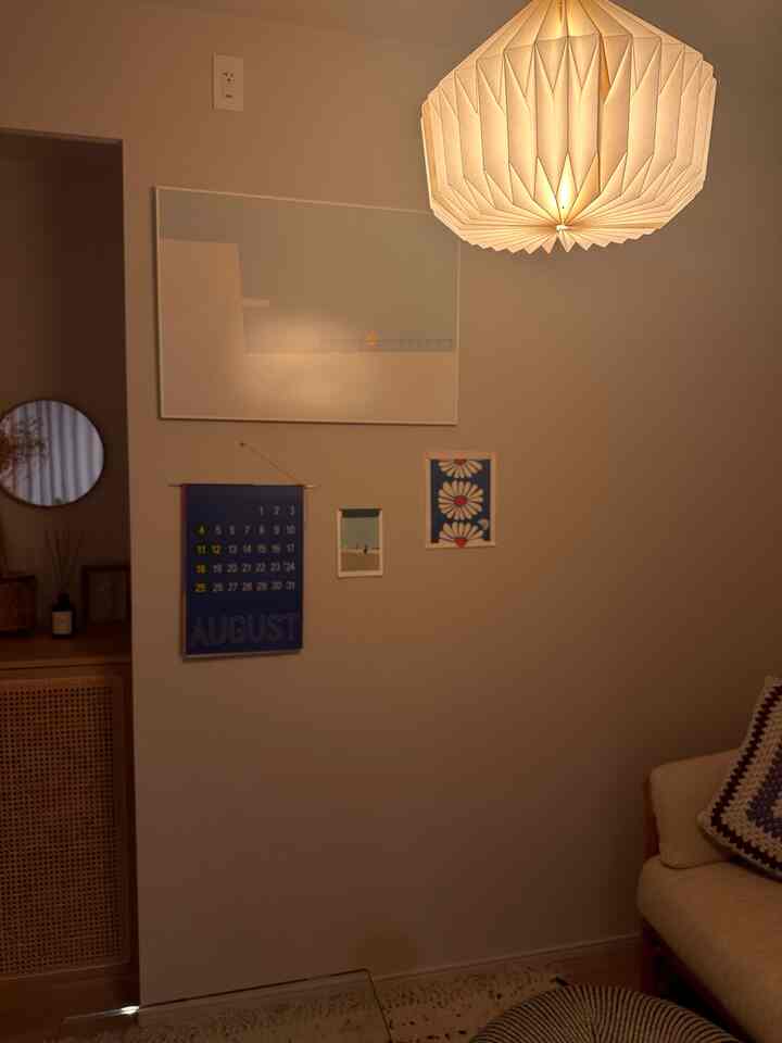 暖かいナチュラルトーンのリビング、大きなペンダントライトとベージュのソファが配置された雰囲気のある空間