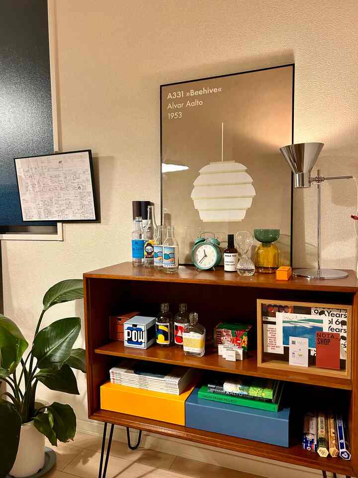 ブラウンのキャビネットと植物、ポスターが配置された自然な雰囲気のリビングインテリア