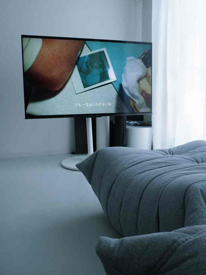 Modern small room in white and gray tones featuring a gray bean bag sofa and TV stand in a home cinema setup