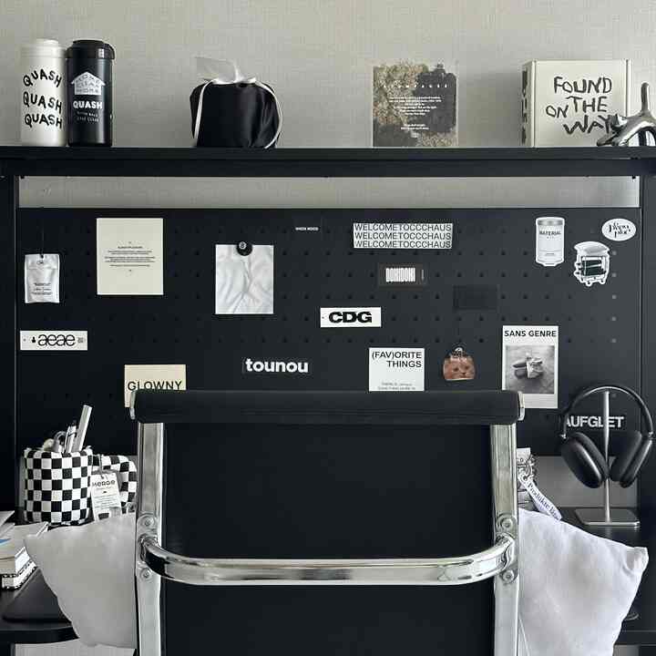 Black-accented home office featuring a black office chair, desk, and shelf with decorative objects against a white wall background for a clean workspace