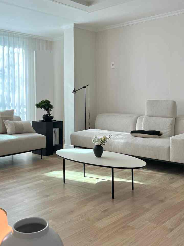 A clean living room in white and wood tones featuring fabric sofas and a coffee table, conveying a modern and natural atmosphere