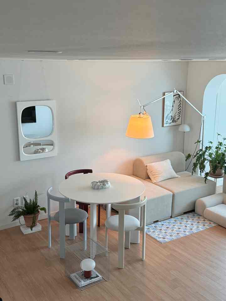 Natural toned living room with white and beige featuring a round dining table and fabric sofa in a modern setting