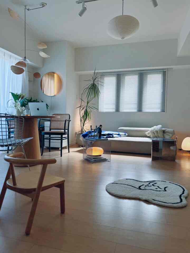 White and wood tone living room featuring low sofa and wooden chairs in a natural, simple setting
