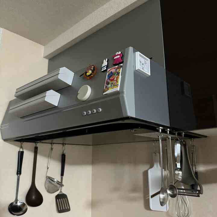 Gray-toned kitchen range hood with hanging cooking utensils in a neat kitchen area